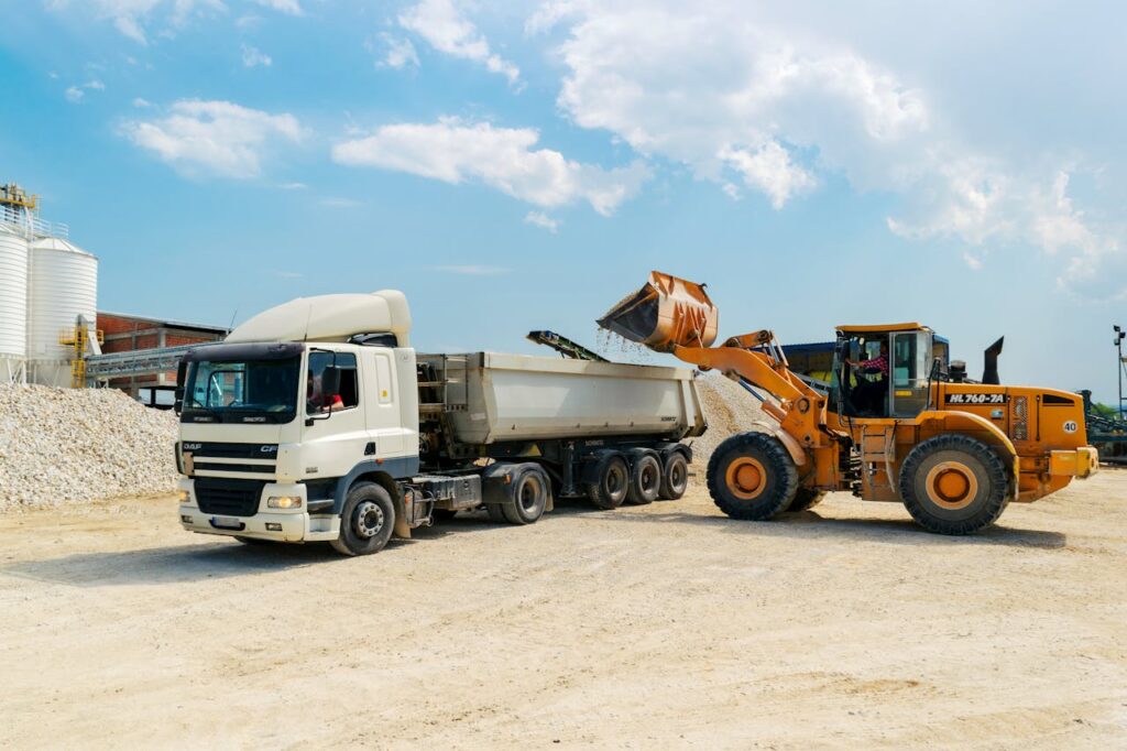 heavy-duty truck Excavator loading materials into a heavy-duty truck at a sunny construction site.